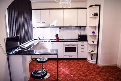 a kitchen with white cabinets and a black counter top at Апартамент Япония in Blagoevgrad