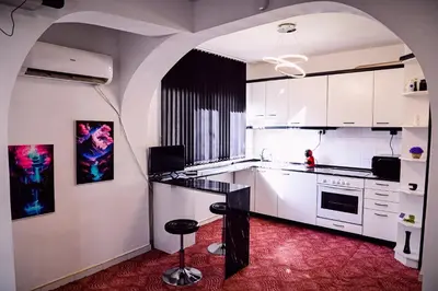 a kitchen with white cabinets and a black counter top at Апартамент Япония in Blagoevgrad