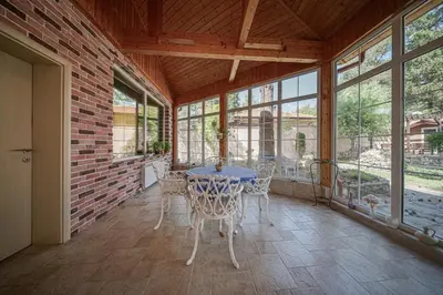 a conservatory with a table and chairs in a room with windows at The Exquisite Residence in Zheleznitsa