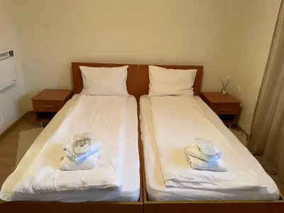 two beds in a room with white sheets and towels at The New Inn in Bansko