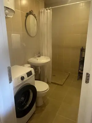 a bathroom with a toilet and a sink with a washing machine at At Marti in Bansko