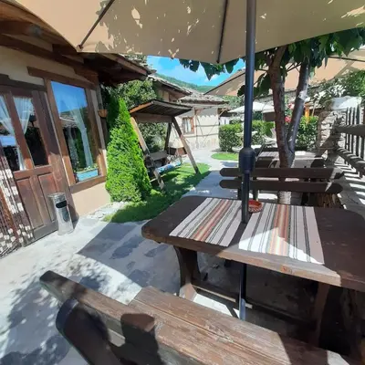a group of picnic tables under an umbrella at Spa&Relax Скендерова Къща in Leshten