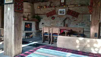 a living room with a fireplace and a table and chairs at Spa&Relax Скендерова Къща in Leshten