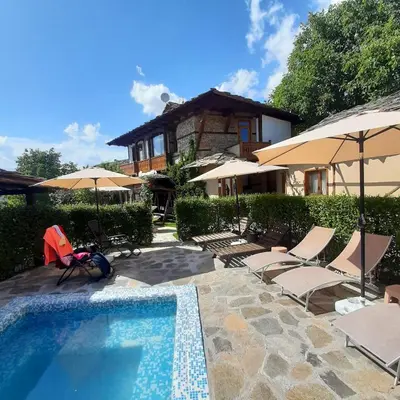 a house with a swimming pool with chairs and umbrellas at Spa&Relax Скендерова Къща in Leshten