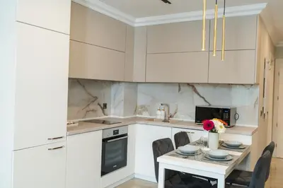 a kitchen with white cabinets and a table with chairs at Simaya, your home in the heart of Sandanski in Sandanski