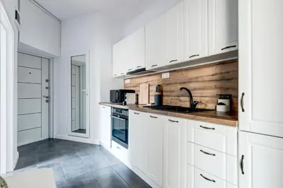 a kitchen with white cabinets and a sink at Cozy Bright Space in the Heart of Women's Market in Sofia