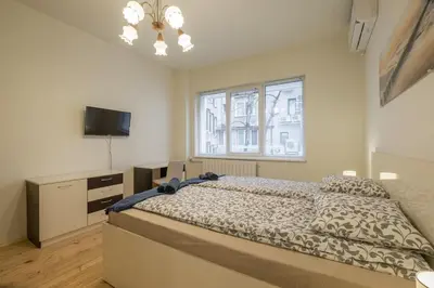 a bedroom with a bed and a tv and a window at Stylish TOP center Flat 100m to Vitosha blvd in Sofia