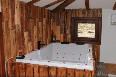 a large white bath tub in a room with a window at Вили Панорама Лещен in Leshten