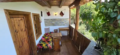 a porch of a house with a bench and a window at Вили Панорама Лещен in Leshten
