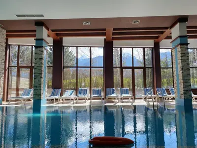 a swimming pool with chairs and windows at AZAX Apartments in Terra Complex in Bansko