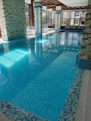 a large pool with blue water in a building at AZAX Apartments in Terra Complex in Bansko