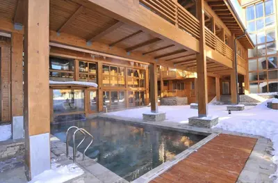 a building with a swimming pool in the snow at Pirin Golf Resort & SPA Two-Bedroom Apartment in Razlog
