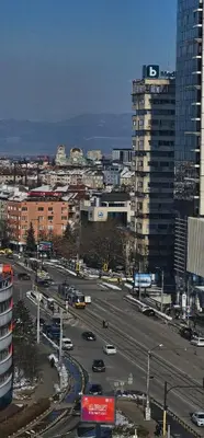 a city with cars driving on a street with buildings at Home away from home in Sofia