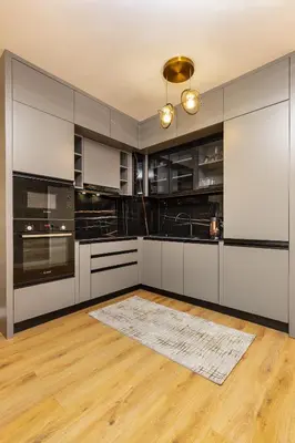 a kitchen with black and white cabinets and a wooden floor at Two-Bedroom Apartments with Free Private Parking and 6min to Center in Plovdiv