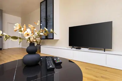 a living room with a television and a vase with flowers at Two-Bedroom Apartments with Free Private Parking and 6min to Center in Plovdiv
