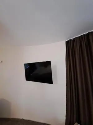 a flat screen tv on a white wall with a curtain at ВасиленаАпарт in Pamporovo