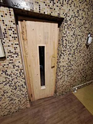 a wooden door in a room with tiled walls at ВасиленаАпарт in Pamporovo