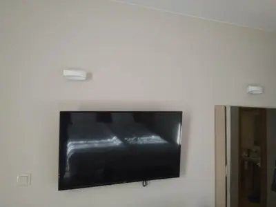 a flat screen tv hanging on a white wall at Георгиев Луксури Апарт in Pamporovo