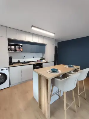 a kitchen with a wooden table and white cabinets at MariGold Apartments in Sandanski