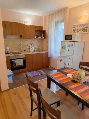 a kitchen with a table and a white refrigerator at Evrika home 4 in Pamporovo