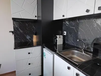 a kitchen with white cabinets and a sink at Mountain Ski & SPA apartment in Pamporovo