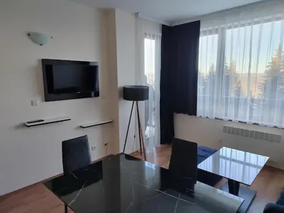 a dining room with a glass table and a television at Mountain Ski & SPA apartment in Pamporovo