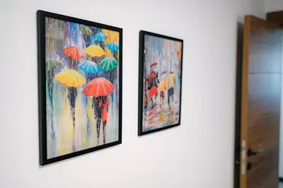 two framed paintings of people with umbrellas on a wall at Top Center in Blagoevgrad