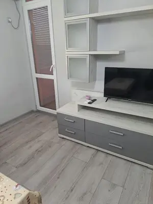 a living room with a flat screen tv on a entertainment center at Удобство - 2 in Petrich