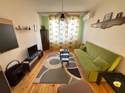 a living room with a green couch and a television at просторен и уютен двустаен в Долен Лозенец - кварталът на артистите in Sofia