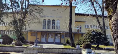 a yellow building with a man standing in front of it at Апартамент Калоян in Banya
