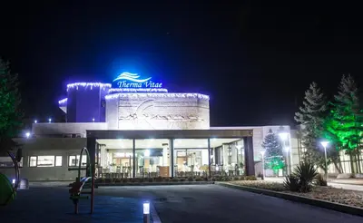 a building with a sign on it at night at Therma Vitae - Профилакториум Огняново in Ognyanovo