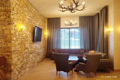 a living room with a table and chairs and a stone wall at Grand Studio A1 in Pamporovo