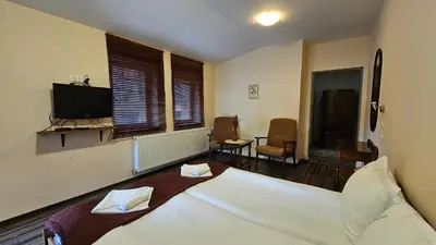 a bedroom with a white bed and a television at Hotel Izvorat Arda - Хотел Изворът Арда in Arda