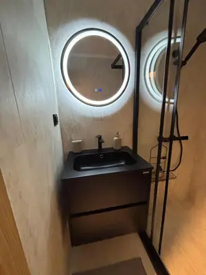 a bathroom with a sink and a round mirror at Ski-in Flat Next to Ski Road at Mountain View in Bansko
