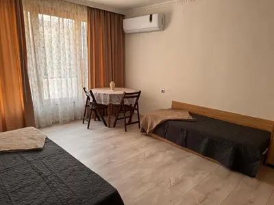 a room with two beds and a table and a window at Апартамент Лилия Сандански in Sandanski