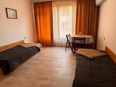 a room with two beds and a table and a window at Апартамент Лилия Сандански in Sandanski