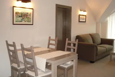 a living room with a table and chairs and a couch at Granat next to Ski Lift by BookVillaBG in Bansko