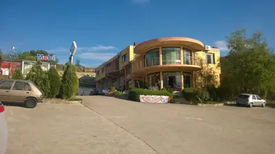 a large building with cars parked in a parking lot at Motel Elegance in Sandanski