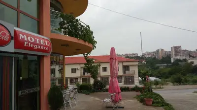 a restaurant with a pink umbrella and chairs and a building at Motel Elegance in Sandanski