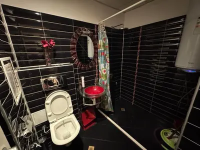 a black tiled bathroom with a toilet and a mirror at Ritz in Sofia