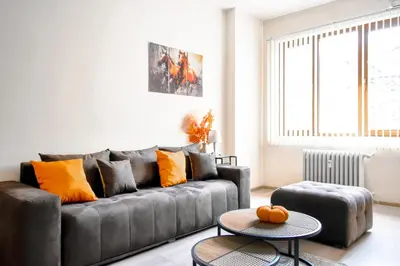 a living room with a gray couch with orange pillows at Orchidea City Centre 1BDR by Flat Mаnager in Sofia