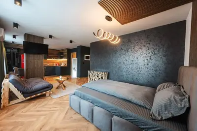 a bedroom with a blue bed and a living room at Уютно студио Verde Suites 14 in Blagoevgrad