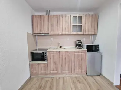 a small kitchen with wooden cabinets and a sink at Апартаменти село Баня in Banya