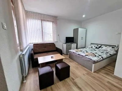a small bedroom with a bed and a table and stool at Апартаменти село Баня in Banya