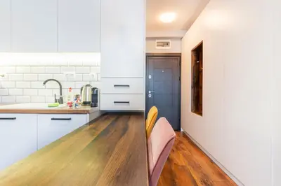a kitchen with white cabinets and a wooden floor at Smart Studio in the heart of Sofia in Sofia