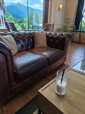 a brown leather couch in a living room with a table at Studio DeLuxe King with mountain view and spa rilski in Bansko