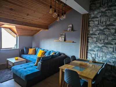 a living room with a blue couch and a table at Nordic Sunset Retreat in Pamporovo