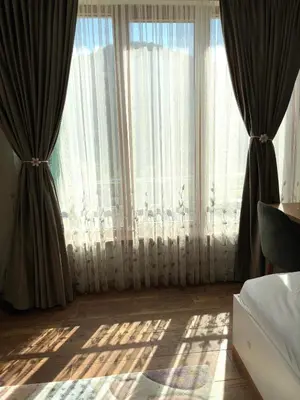 a bedroom with large windows with curtains and a bed at Luxury Park Villa in Sandanski