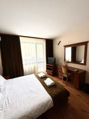 a hotel room with a bed and a desk and a mirror at Къща за гости Стефани in Devin