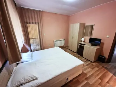 a bedroom with a bed and a desk with a television at Ивелия Къща за гости in Dospat